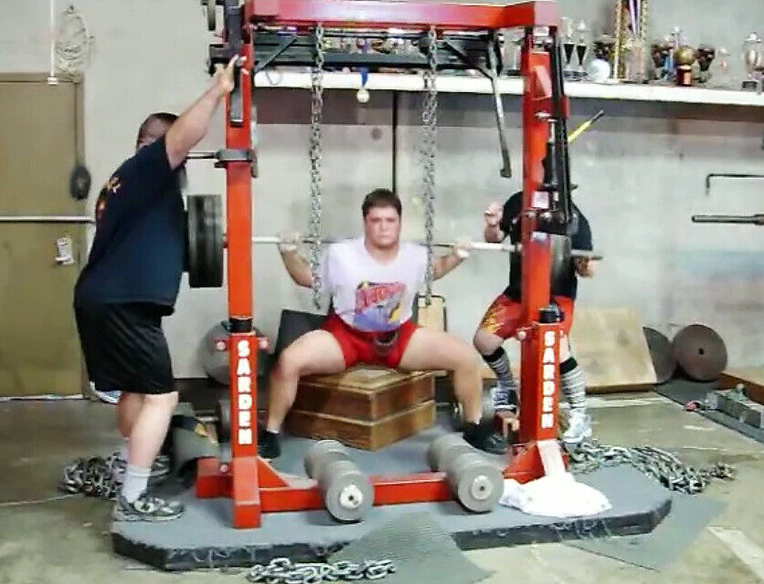 Orry Elor box-squatting in a monolift at Diablo Barbell, a spotter on each side