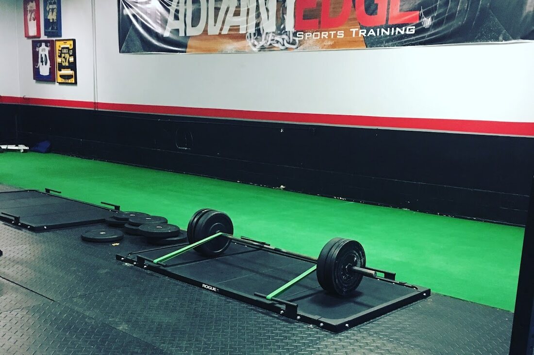 The AdvantEdge Sports Training gym in Marquette, Michigan, turf, a Rogue jack, and a loaded barbell